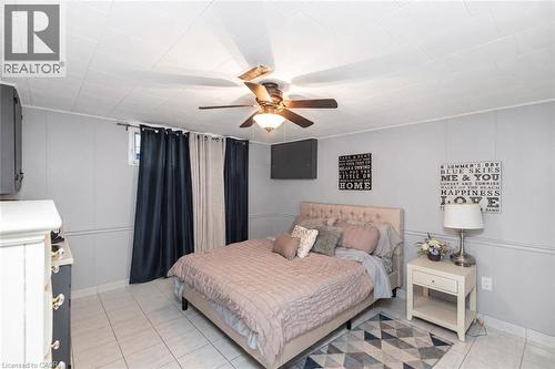 Interior room featuring neutral-toned walls, tile flooring, a grid-patterned ceiling, and a central ceiling fan with integrated lighting - 43 Alderney Avenue, Hamilton, ON 