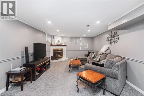 Finished lower level featuring a white-painted brick corner fireplace with a wooden mantel, recessed lighting, and carpeting - 43 Alderney Avenue, Hamilton, ON 