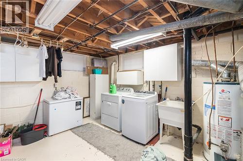 Utility area featuring painted masonry walls, exposed ceiling joists, wall-mounted cabinetry, and a deep basin utility sink - 43 Alderney Avenue, Hamilton, ON 