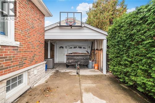 Detached garage featuring a concrete driveway, mounted basketball hoop, and white siding - 43 Alderney Avenue, Hamilton, ON 