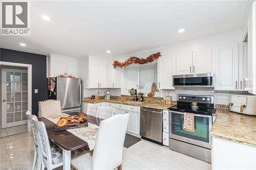Kitchen featuring white cabinetry, stone countertops, stainless steel appliances, and a tiled floor - 43 Alderney Avenue, Hamilton, ON 