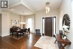 Wood-finish flooring throughout, featuring a dark wood paneled entry door with sidelights, a contemporary chandelier, and a recessed ceiling with integrated lighting - 