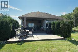 Expansive concrete patio with a covered outdoor living space, exterior stone siding, and a gabled roofline - 