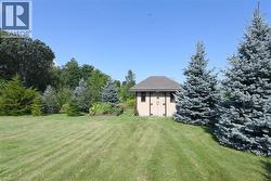 Expansive grassy area with a storage building featuring a shingled roof and double doors - 