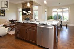 Kitchen island with granite countertop, integrated sink, and stainless steel dishwasher - 