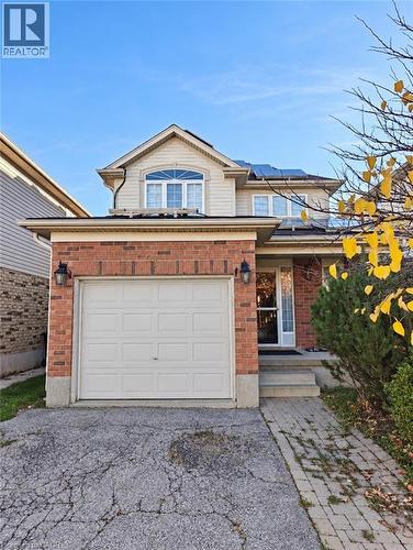 Two-story residence featuring a brick and vinyl siding exterior, attached single-car garage, roof-mounted solar panels, and a paved stone walkway - 52 Isabella Street, Kitchener, ON 