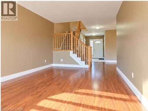 Wood-finish flooring, staircase with natural wood railings, and exterior entry door with glass paneling - 52 Isabella Street, Kitchener, ON 