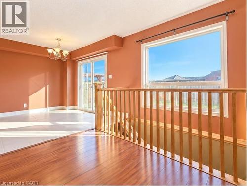Interior space featuring wood-finish flooring, a traditional wood spindle railing, oversized windows, sliding glass door, and a multi-arm chandelier - 52 Isabella Street, Kitchener, ON 