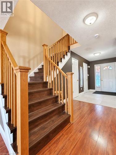 Foyer entry featuring wood-finish flooring, a staircase with light wood railing and balusters, and a solid-core front door with decorative glass paneling - 52 Isabella Street, Kitchener, ON 
