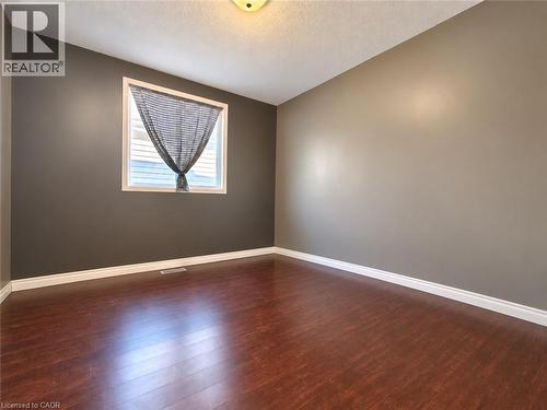 Room featuring dark wood-finish flooring, two-tone wall paint, and a single window with a white frame - 52 Isabella Street, Kitchener, ON 