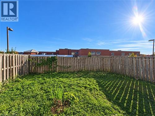 Fenced backyard featuring a grass lawn and two metal light poles - 52 Isabella Street, Kitchener, ON 