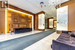 Lobby featuring wood-panel accent walls with integrated lighting, backlit stone pillars, tile flooring, and a decorative bubble chandelier - 