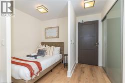 Wood-finish flooring, sliding glass-panel closet doors, flush-mount square ceiling lighting, and solid-core interior door - 
