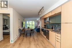 Kitchen featuring flat-panel wood-finish cabinetry, stainless steel appliances, a glass backsplash, and wood-finish flooring - 