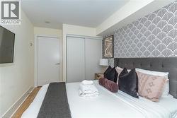 Bedroom featuring wood-finish flooring, sliding door closet, and patterned accent wall - 