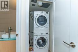 Laundry closet featuring a stackable washer and dryer unit, and a bathroom vanity with a vessel sink and single-handle faucet - 