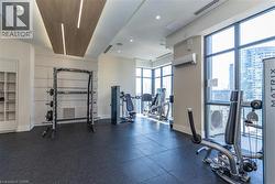 Fitness room featuring floor-to-ceiling windows, rubber flooring, wood-finish ceiling architectural detail with integrated lighting, and wall-mounted climate control - 