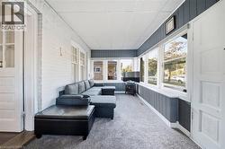 Enclosed porch featuring white painted brick walls, vertical paneled wainscoting, multiple large windows, and paneled exterior doors - 