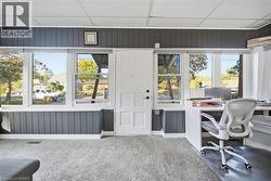 Interior space featuring dark vertical paneled walls, a white multi-panel entry door, and expansive windows with roller shades - 