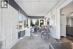 Sunroom featuring painted brick walls, vertical wood-paneling, built-in shelving, and large windows - 