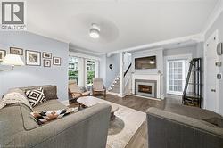 Living room featuring wood-finish flooring, a fireplace with a decorative tile surround and white mantel, crown molding, and a multi-pane glass door - 
