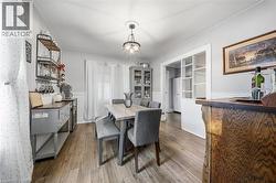 Dining area featuring wood-finish flooring, wainscoting, a multi-light pendant fixture, and glass-paned room dividers - 