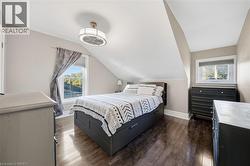 Bedroom featuring vaulted ceilings, wood-finish flooring, and a modern drum-style ceiling fan with integrated lighting - 