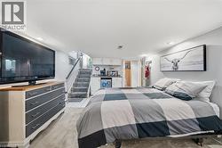 Lower-level space featuring recessed lighting, built-in kitchenette cabinetry, a sink, and carpeted flooring with stair access - 