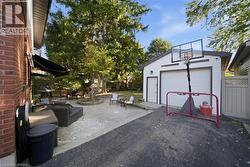 Outdoor concrete patio featuring a stone-bordered garden bed, detached garage with white siding, and privacy fencing - 