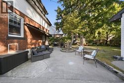 Concrete patio with a stone-bordered tree planter, brick exterior facade, and private backyard - 