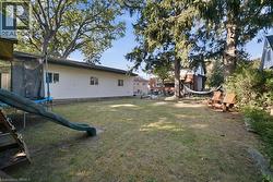 Expansive backyard featuring mature trees, lawn, and horizontal vinyl siding exterior - 
