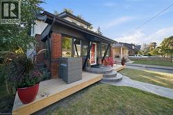 Exterior facade featuring red brick masonry, wood-finish decking, curved concrete entry stairs, and large glass pane windows - 