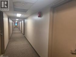 Interior hallway featuring neutral walls, carpeting, recessed drop-ceiling panels, and integrated linear lighting - 