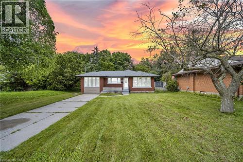 Brick exterior with a dark-pitched roof, front yard with a concrete driveway, and mature trees - 284 Cedar Crescent, Cambridge, ON - Outdoor