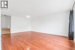 Bright interior space featuring wood-finish flooring, white walls, and a recessed ceiling light fixture - 