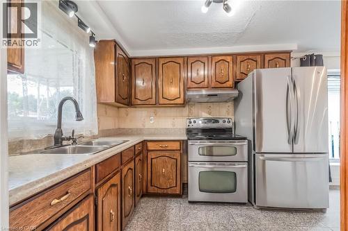Kitchen featuring wood cabinetry, stainless steel appliances, a double basin sink, and track lighting - 1259 Ernest Avenue, London, ON - Indoor Photo Showing Kitchen With Double Sink