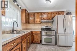 Kitchen featuring wood cabinetry, stainless steel appliances, a double basin sink, and track lighting - 