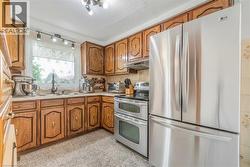 Kitchen featuring wood cabinetry, stainless steel French door refrigerator, stainless steel electric range with double oven, a single basin sink with a gooseneck faucet, and tile flooring - 