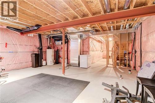 Unfinished basement featuring white refrigerator, gas water heater, and a water softener system - 239 Cranbrook Street, Kitchener, ON - Indoor Photo Showing Basement