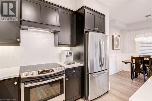 Kitchen featuring stainless steel appliances, light wood-style flooring, a wainscoted wall, a decorative wall, and light stone countertops - 239 Cranbrook Street, Kitchener, ON - Indoor Photo Showing Kitchen