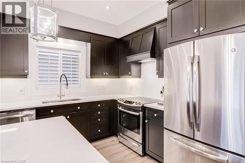 Kitchen featuring stainless steel appliances, hanging light fixtures, light wood-style floors, and light stone counters - 239 Cranbrook Street, Kitchener, ON - Indoor Photo Showing Kitchen