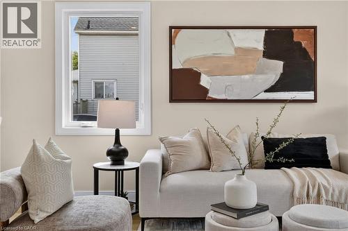 Light-toned wall paint, a framed window, a large rectangular artwork, and light wood-finish flooring - 174 London Street N, Hamilton, ON - Indoor Photo Showing Living Room