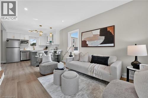 Open-concept living space featuring wood-finish flooring, recessed lighting, and a kitchen with white cabinetry, stainless steel appliances, and a breakfast bar - 174 London Street N, Hamilton, ON - Indoor Photo Showing Living Room