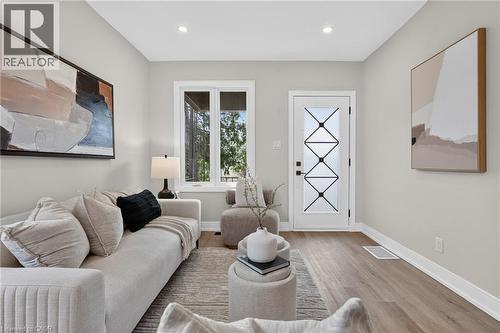 Living area featuring wood-finish flooring, recessed lighting, a decorative entry door with frosted glass, and a large window - 174 London Street N, Hamilton, ON - Indoor Photo Showing Living Room