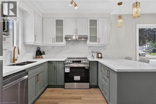 U-shaped kitchen featuring two-tone cabinetry, stainless steel appliances, and wood-finish flooring - 174 London Street N, Hamilton, ON - Indoor Photo Showing Kitchen