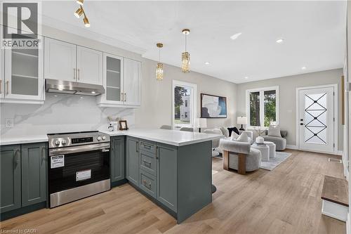 Open-concept kitchen featuring two-tone cabinetry, stainless steel appliances, and wood-finish flooring - 174 London Street N, Hamilton, ON - Indoor Photo Showing Kitchen With Double Sink With Upgraded Kitchen