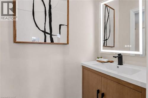 Modern bathroom featuring a wood-finish vanity with white quartz countertop, rectangular vessel sink, and matte black wall-mounted faucet - 174 London Street N, Hamilton, ON - Indoor Photo Showing Bathroom
