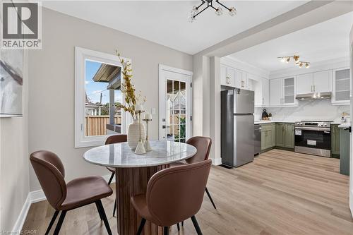 Kitchen featuring stainless steel appliances, two-tone cabinetry, and wood-finish flooring - 174 London Street N, Hamilton, ON - Indoor Photo Showing Other Room