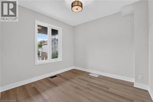 Wood-finish flooring, white trim, and a contemporary ceiling light fixture - 174 London Street N, Hamilton, ON - Indoor Photo Showing Other Room