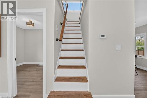 Staircase with wood-finish treads and white risers, wood-finish railing, and light-toned wall paint - 174 London Street N, Hamilton, ON - Indoor Photo Showing Other Room
